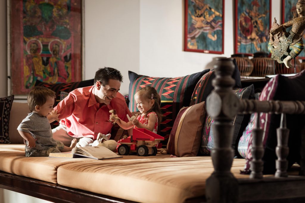 A man sits on a couch with his children while on holiday at Four Seasons Resort in Chiang Mai