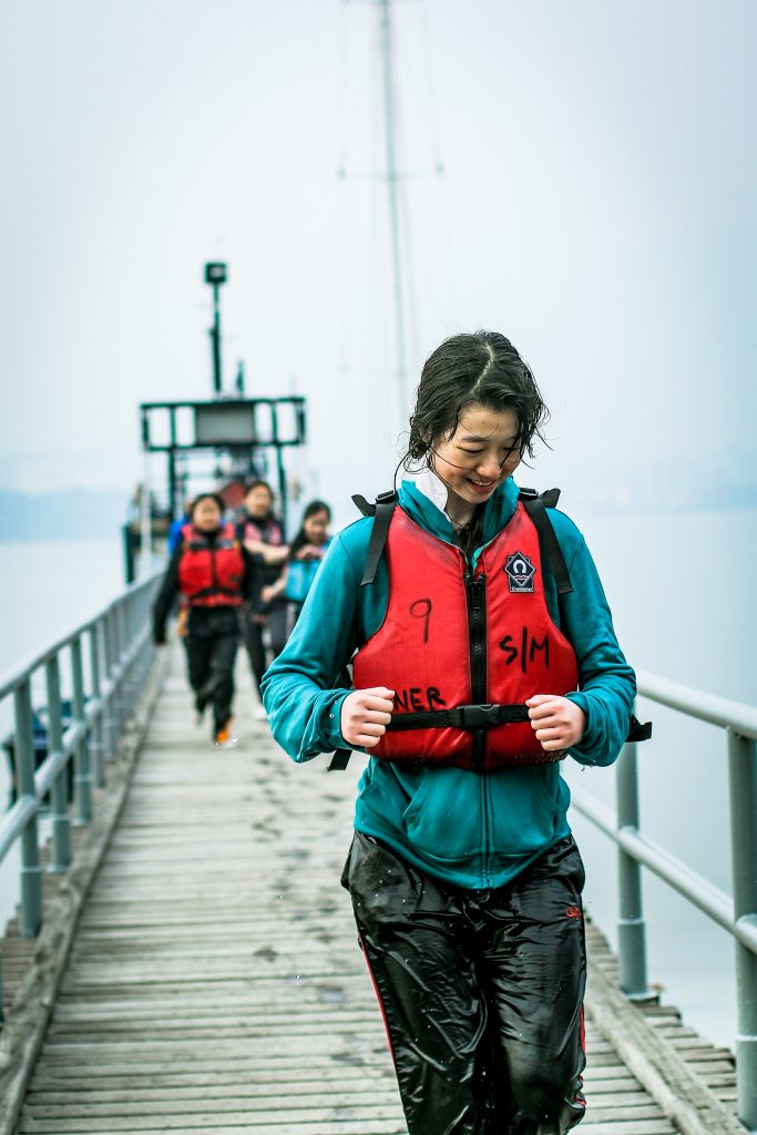 A woman runs with a life jacket on along a pier during an event with Outward Bound