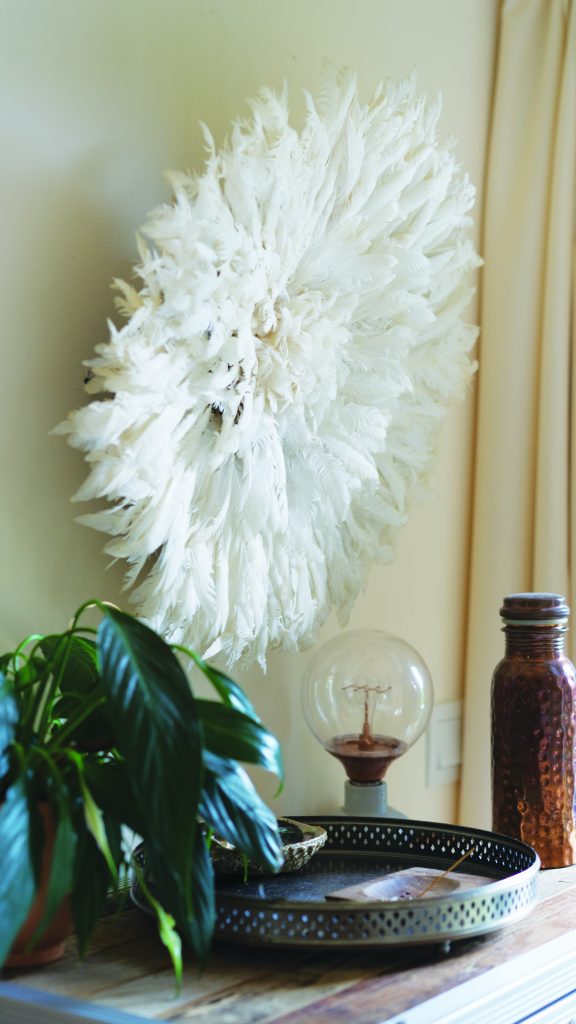 Decorative items, including a feather wall ornament and a copper water bottle.