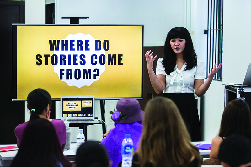 A woman stands in front of a screen with the words "Where do stories come from?" on it, as part of the Hong Kong International Literary Festival