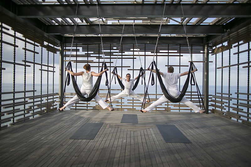 3 people do aerial yoga in at a retreat in Bali.