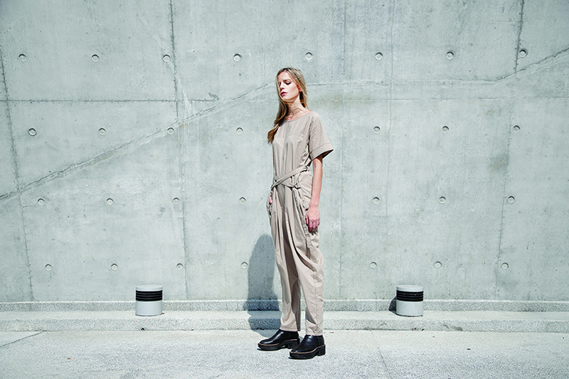 A woman in a beige jumpsuit made from sustainable materials. 