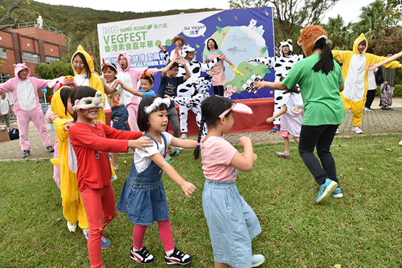 A group of children play in front of a banner for VegFest, a vegan festival in Hong Kong