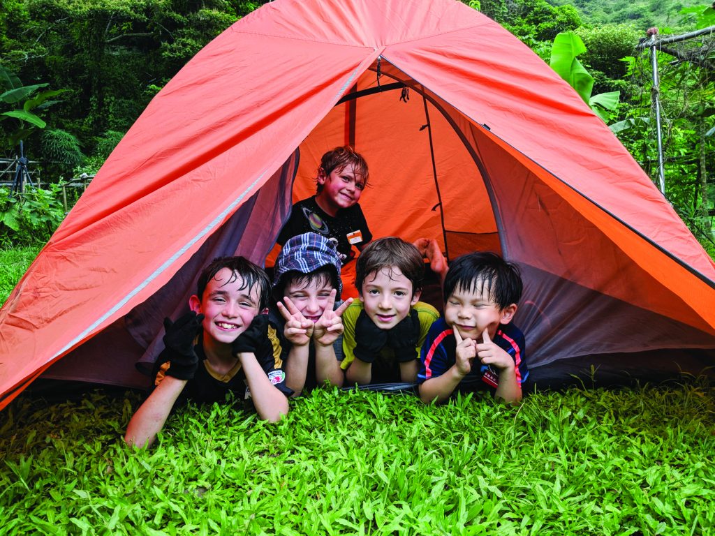 A group of small children smile from inside a tent at Ark Eden, a family-friendly camping site in Hong Kong.