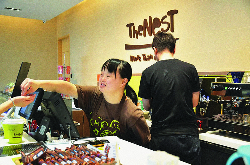 A woman with disabilities gives changes to a customer at social enterprise cafe run by charity The Nesbitt Centre in Hong Kong.