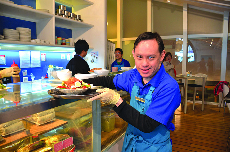 A man with disabilities holds a plate of food at a social enterprise cafe run by The Nesbitt Centre, a charity in Hong Kong. 