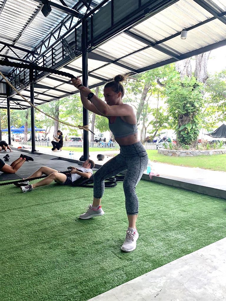 A woman works out strenuously in a gym, part of her self care routine.