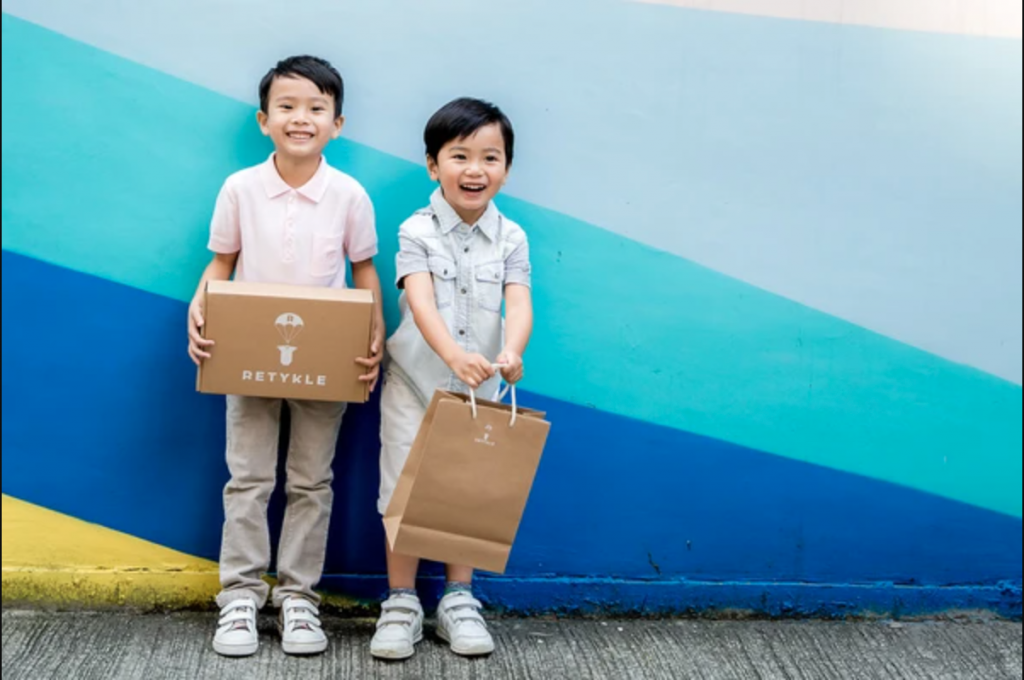 Two children hold Retykle bags, from a secondhand fashion shop in Hong Kong. 